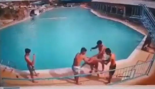  
Nhóm bạn xoay nam thanh niên vài vòng trên thành bể bơi (Ảnh: Cắt từ clip)