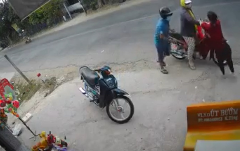  
Người đàn ông áo xanh vờ can ngăn để người phụ nữ phóng xe tẩu thoát. (Ảnh: Chụp màn hình)