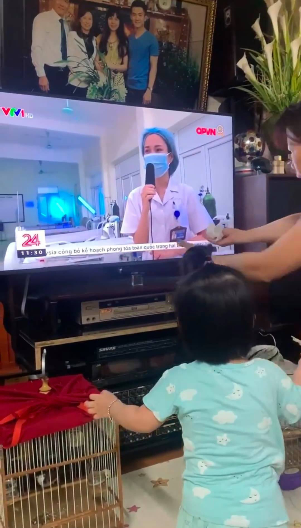  
Bé gái giơ tay đòi bế khi thấy mẹ trên tivi. (Ảnh: H.M.)