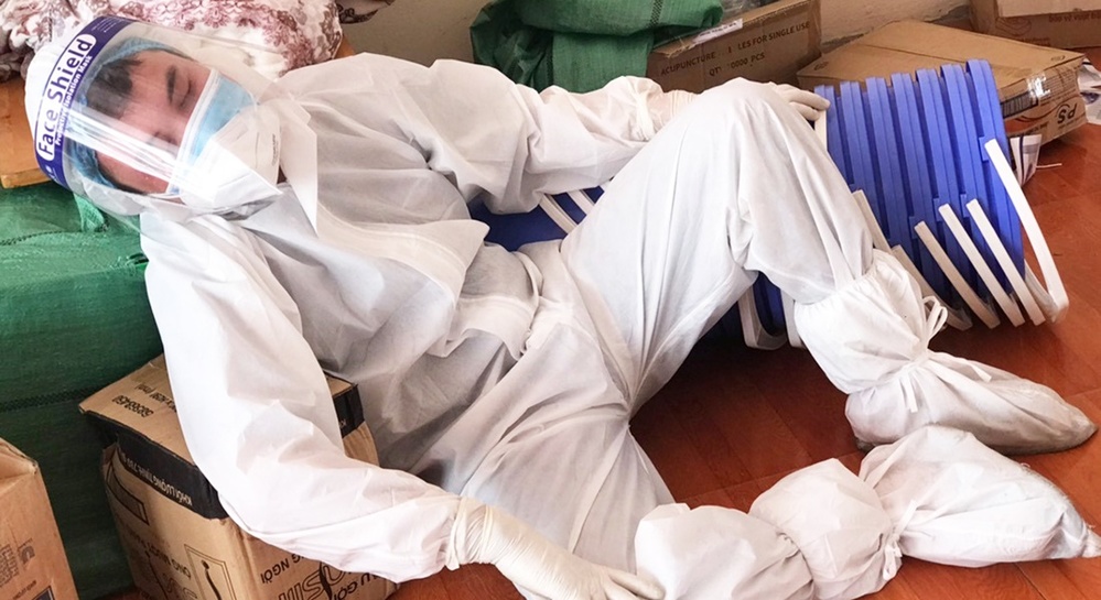  
Một nhân viên y tế nghỉ mệt khi bộ đồ bảo hộ vẫn còn trên người. (Ảnh: VnExpress)