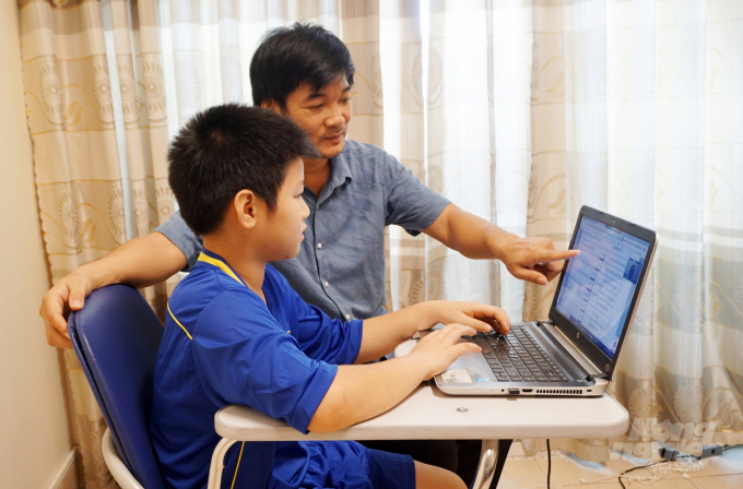  
Học sinh cấp 1 học trực tuyến dưới sự hướng dẫn của phụ huynh. (Ảnh: Báo Nông nghiệp Việt Nam)