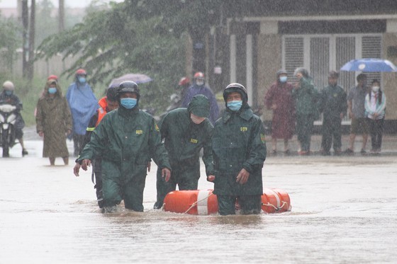 
Mặc mưa lớn, lực lượng chức năng vẫn lội qua dòng nước chảy xiết để đưa học sinh ra nơi an toàn. (Ảnh: Sài Gòn Giải Phóng)
