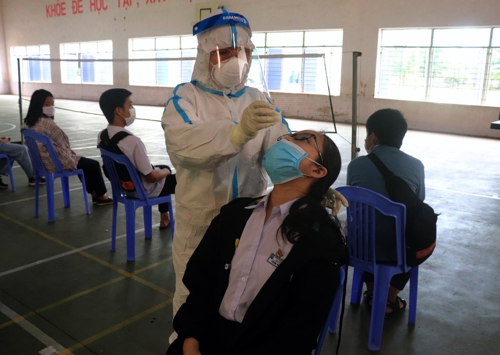  
Nhân viên y tế đang lấy mẫu xét nghiệm cho các em học sinh. (Ảnh: Báo Chính Phủ)