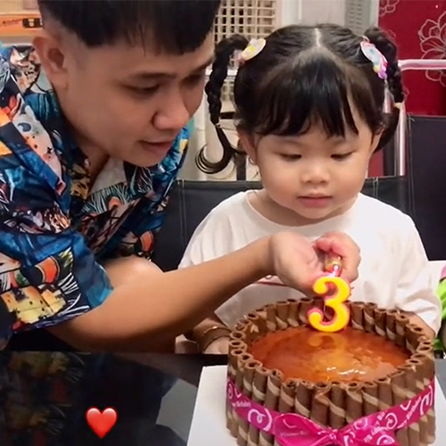 
Bé được bố giúp thổi nến. (Ảnh: Chụp màn hình)