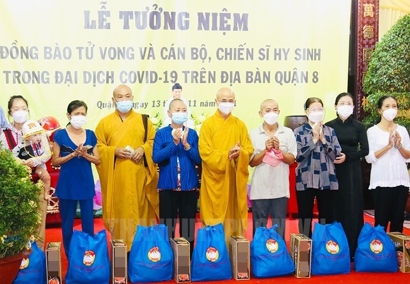 Các gia đình bị ảnh hưởng dịch Covid-19 nhận quà hỗ trợ trong buổi lễ tưởng niệm tại chùa Long Hoa. (Ảnh: Thành Ủy TP.HCM)