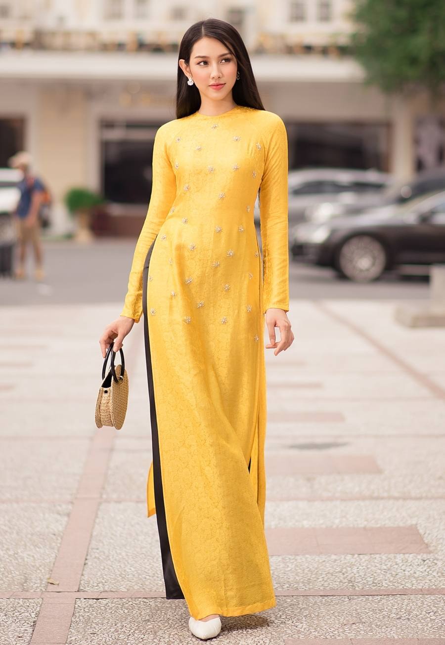  
Miss Grand International lựa chọn kiểu Áo dài chất gấm có họa tiết hoa đơn giản trên nền vàng đậm chất xưa cũ. (Ảnh: FB Nguyễn Thúc Thùy Tiên)
