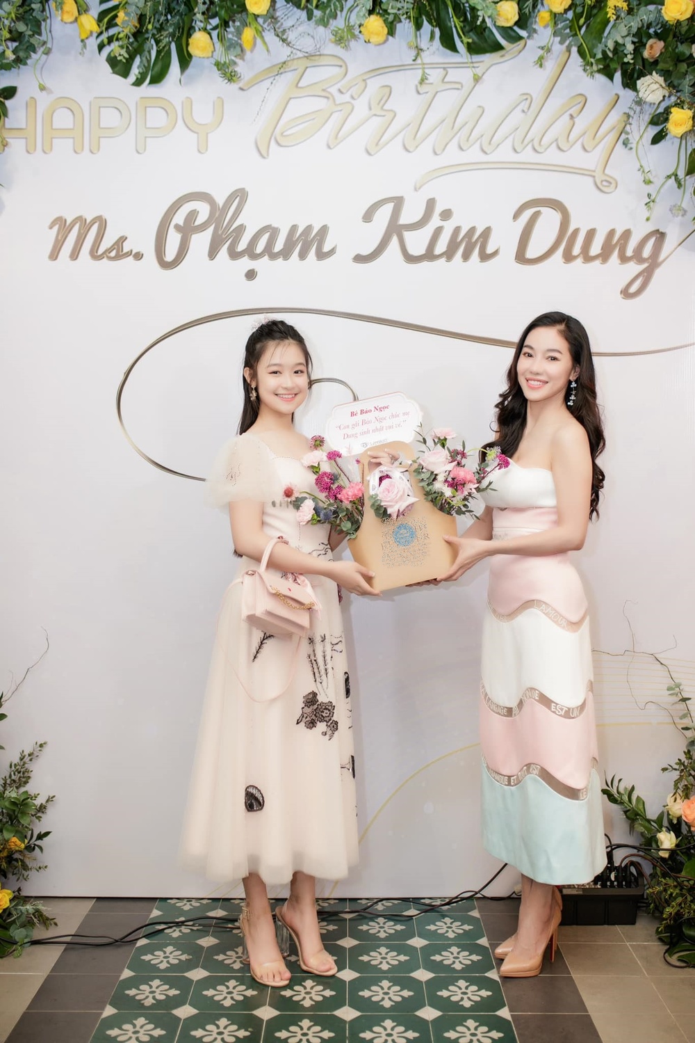 
Ở tuổi 14, bé Bảo Ngọc khoe vẻ đẹp dịu dàng trong thiết kế đầm xòe nữ tính, tặng hoa chúc mừng sinh nhật mẹ nuôi. 
