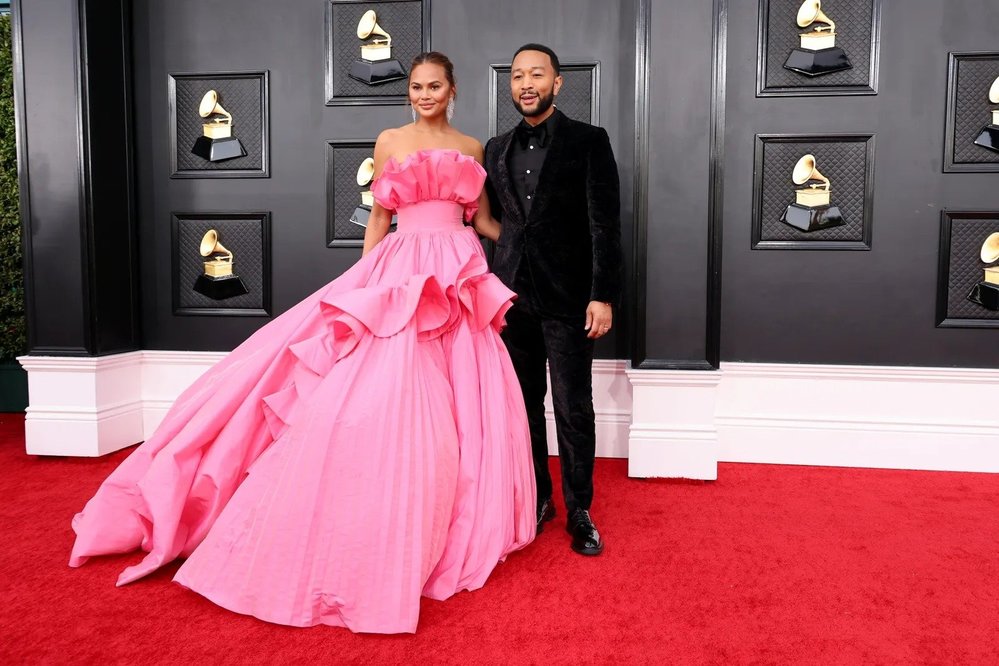 John Legend và Chrissy Teigen đến thảm đỏ. Teigen tham gia cùng Billy Porter trong việc chọn một chiếc váy hoa vân anh cho giải Grammy.