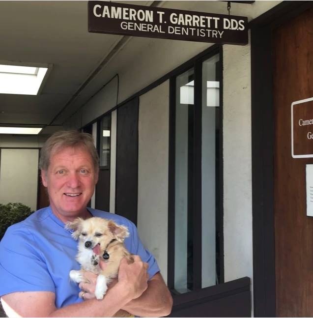  Tiến sĩ Cameron Garrett bế Karma, chú chó trị liệu nha khoa đầu tiên của ông. (Ảnh: today)