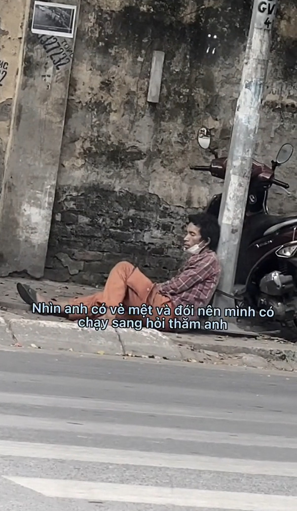    Người đàn ông với dáng vẻ mệt mỏi nằm tạm bợ phía bên đường. (Ảnh: Chụp màn hình TikTok N.)