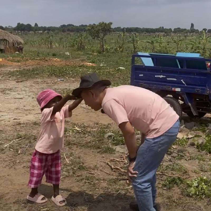  Em còn tự tay đội mũ cho chú Tiến Nguyễn. (Ảnh: YouTube Tiến Nguyễn - Cuộc sống châu Phi)