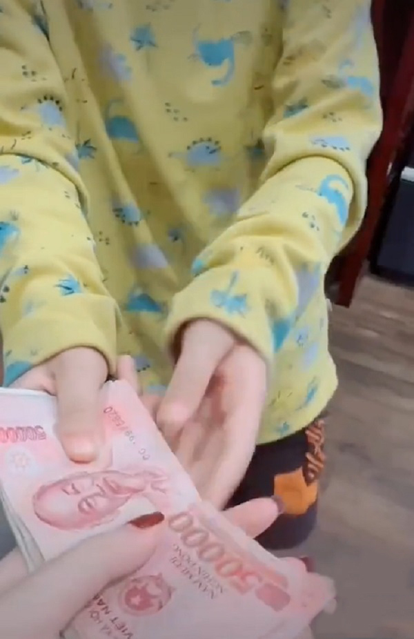  Cậu bé lễ phép đưa số tiền mà mình tiết kiệm được cho mẹ đóng học. (Ảnh: Cắt từ clip TikTok N.T.T)