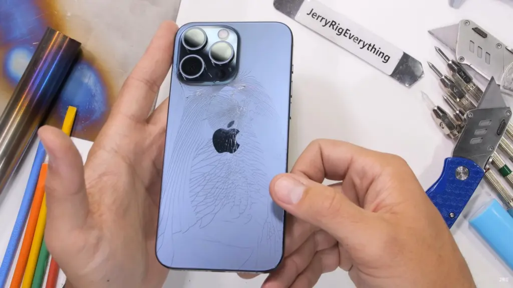  
Mặt kính iPhone 15 Pro Max bị nứt sau khi bị bẻ bằng tay không. (Ảnh: JerryRigEverything)